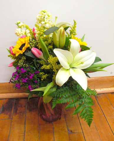 A vase full of beautiful spring flowers like lilies and tulips.