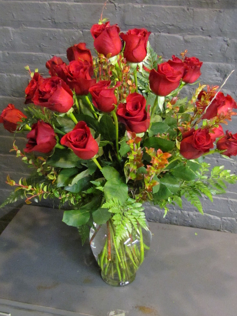 24 roses with greens in a glass vase