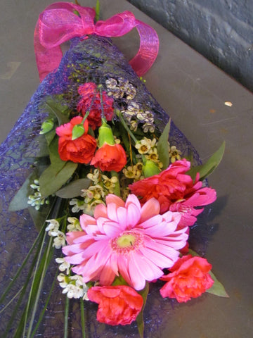 Small bouquet of cheerful flowers in mesh wrapping